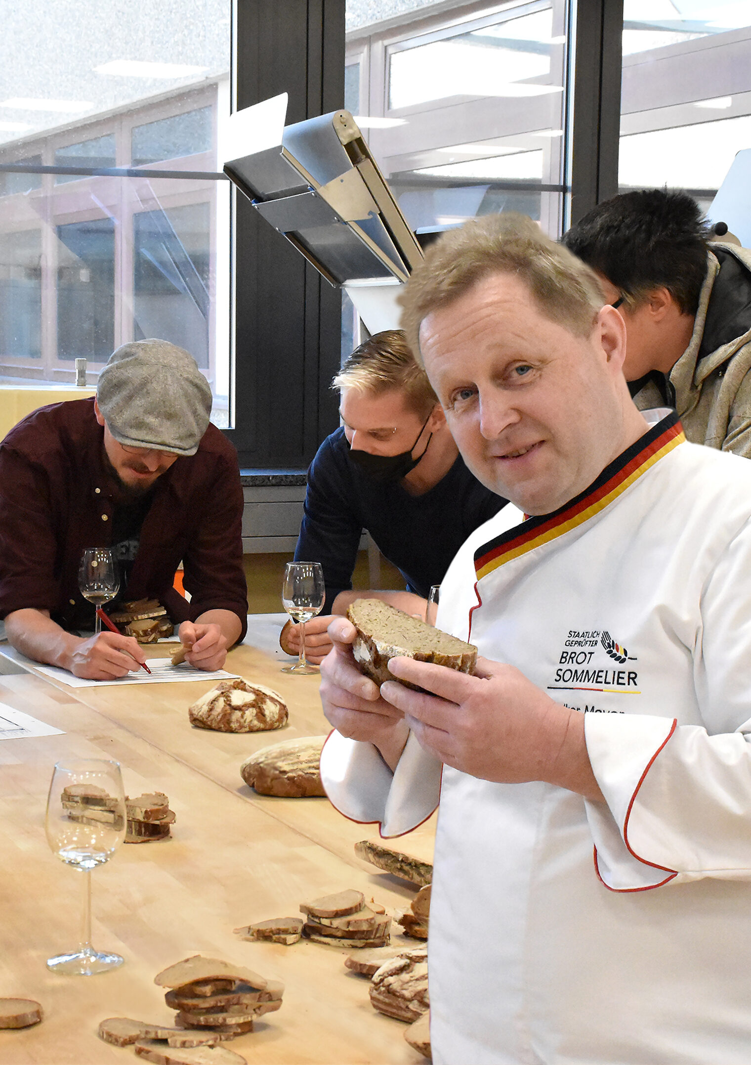 Der Brotsommelier Volker Mayer lächelt freundlich in die Kamera und präsentiert dabei ein Stück Brot.