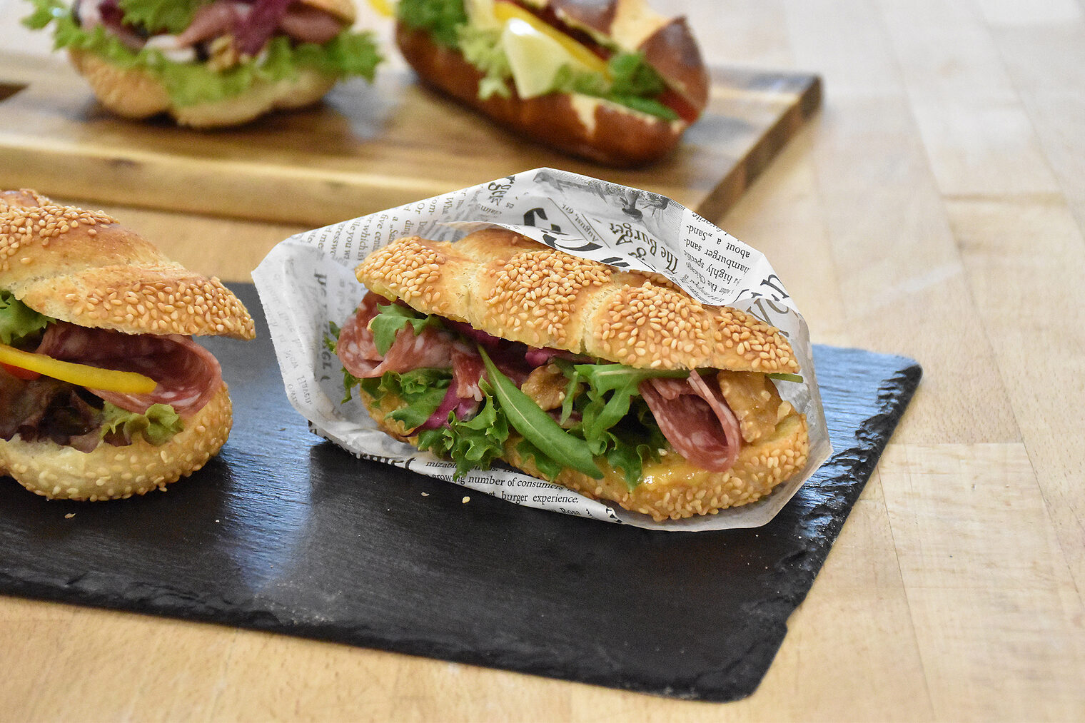 Belegte Brötchen mit Wurst und Salat präsentiert auf einem Schneidebrett.