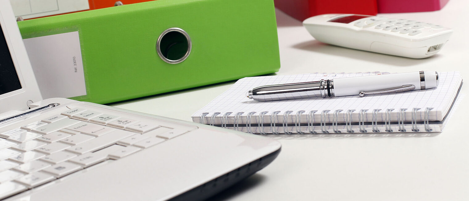 Büroorganisation Laptop, Aktenordner, Stift und Telefon liegen auf Schreibtisch