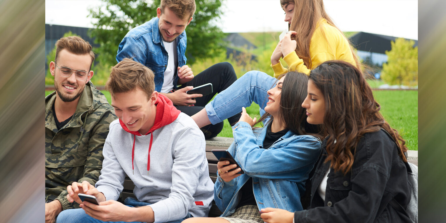 Jugendliche Gruppe sitzt zusammen und schaut auf Smartphones