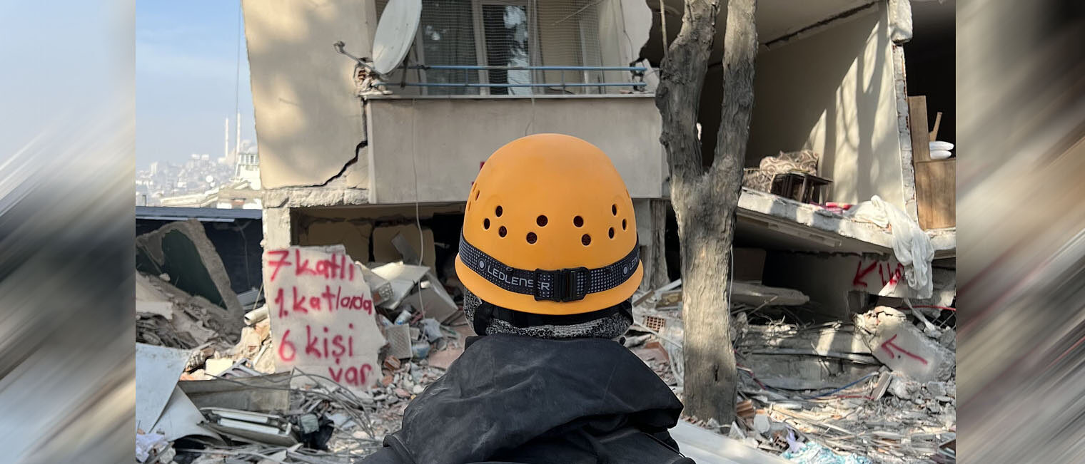 Mann mit Helm steht vor der Ruine eines Hochhauses