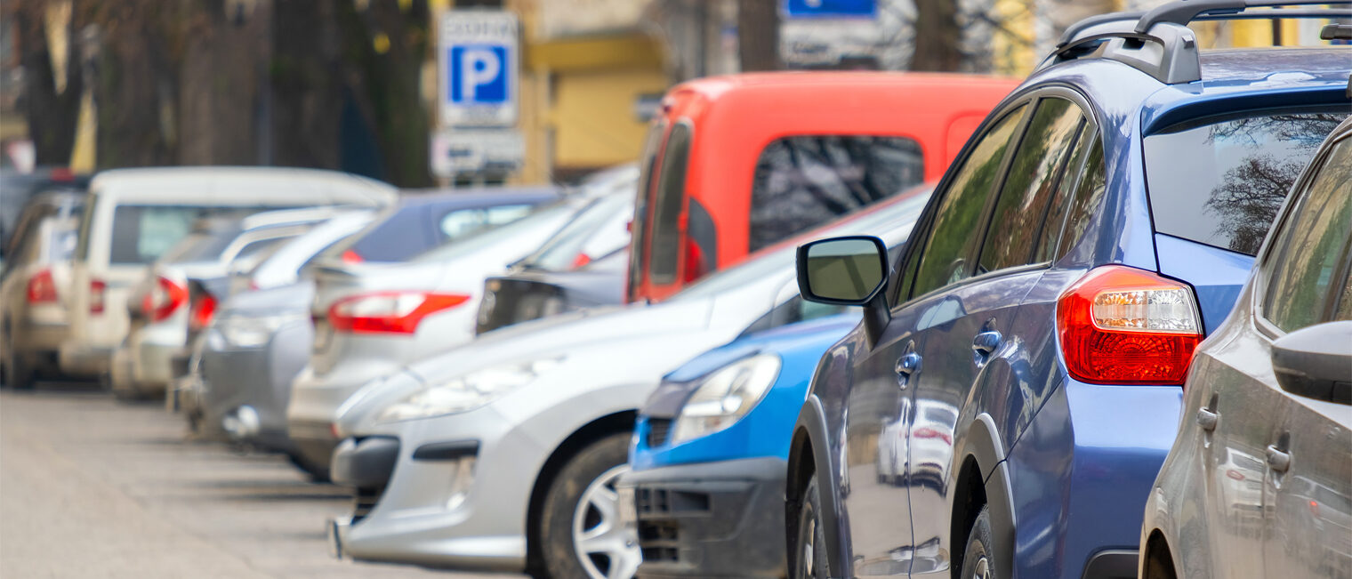 Straße in einer Stadt mit vielen parkenden Fahrzeugen