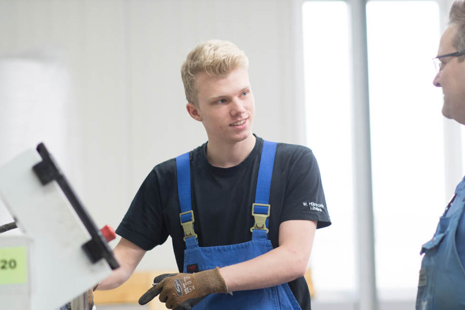 Auszubildender in Werkstatt und Ausbilder unterhalten sich