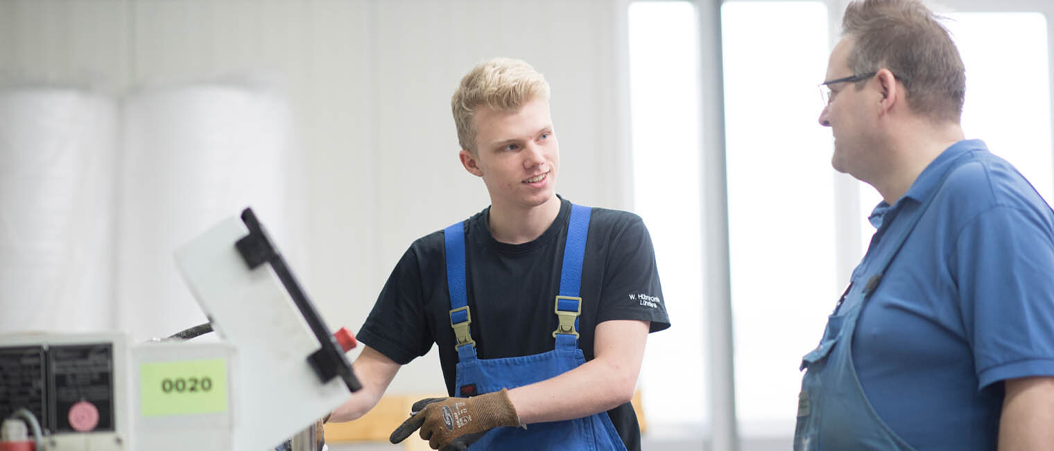 Tipps Ausbildungsstart Auszubildender in Werkstatt und Ausbilder unterhalten sich