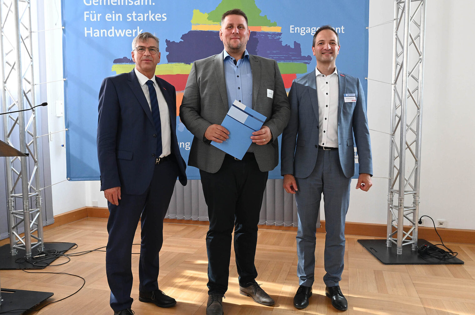 Gruppenfoto von Ehrungsveranstaltung mit drei Personen