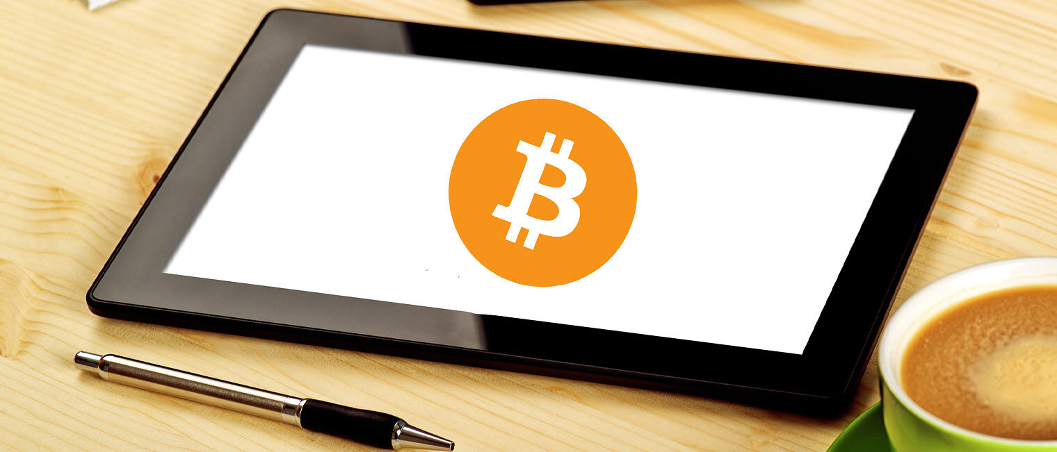 Webinar digitale Zahlungsmittel Tablet auf einem Tisch mit dem Icon einer Kryptowährung auf dem Bildschirm