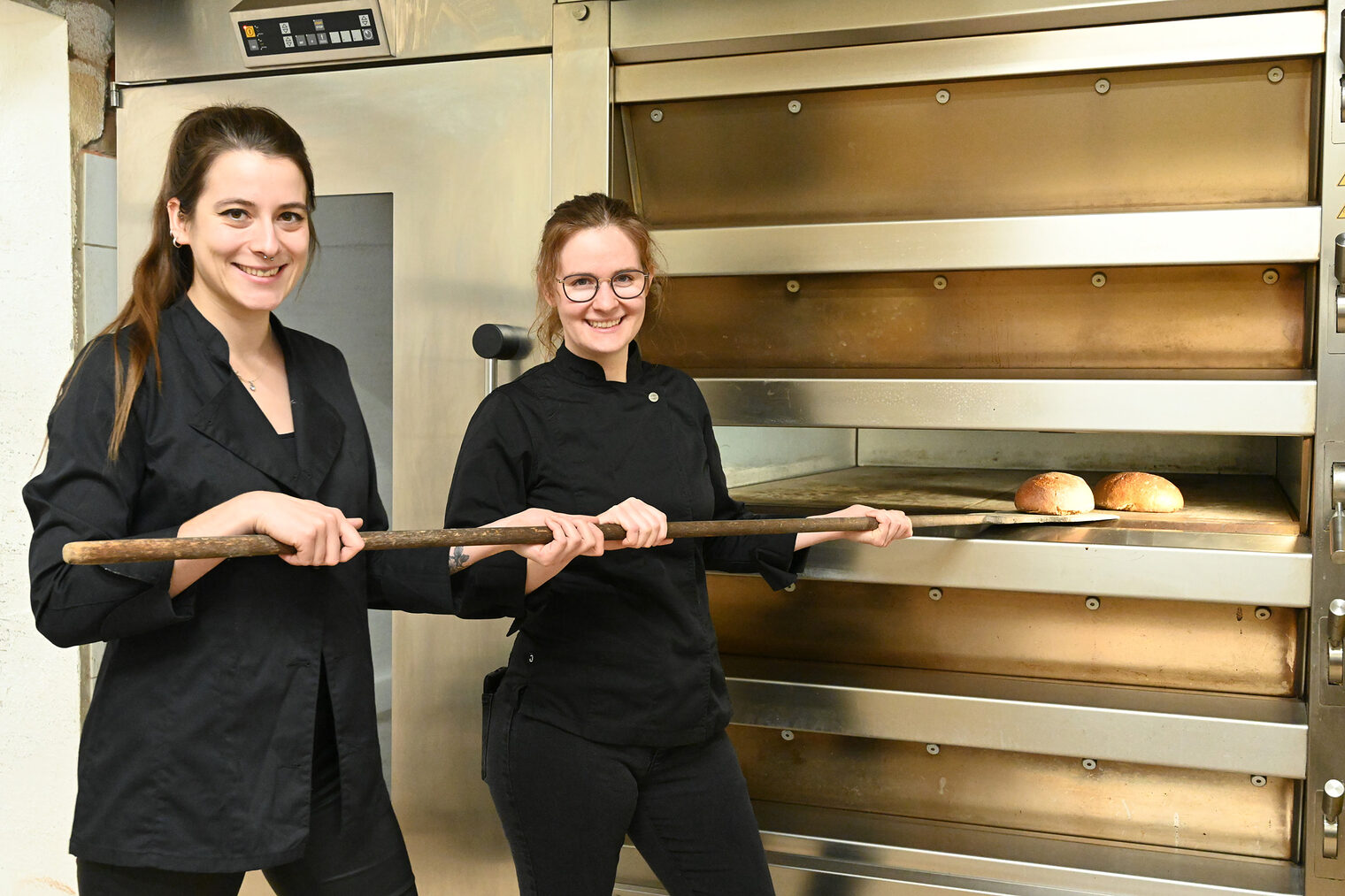 Bäckerinnen am Backofen, schieben Brote hinein