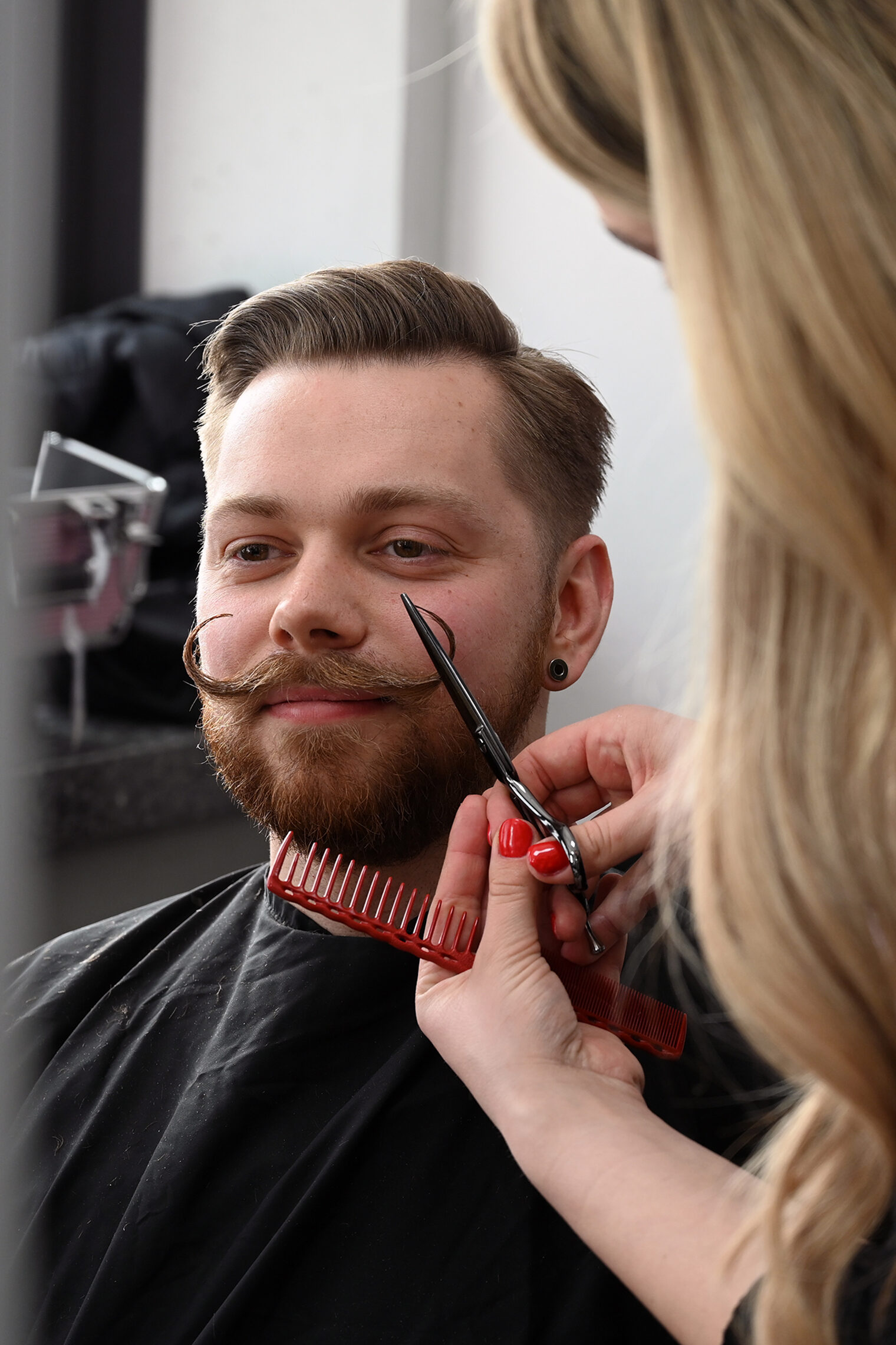 Friseurin schneidet einen Schnurrbart.