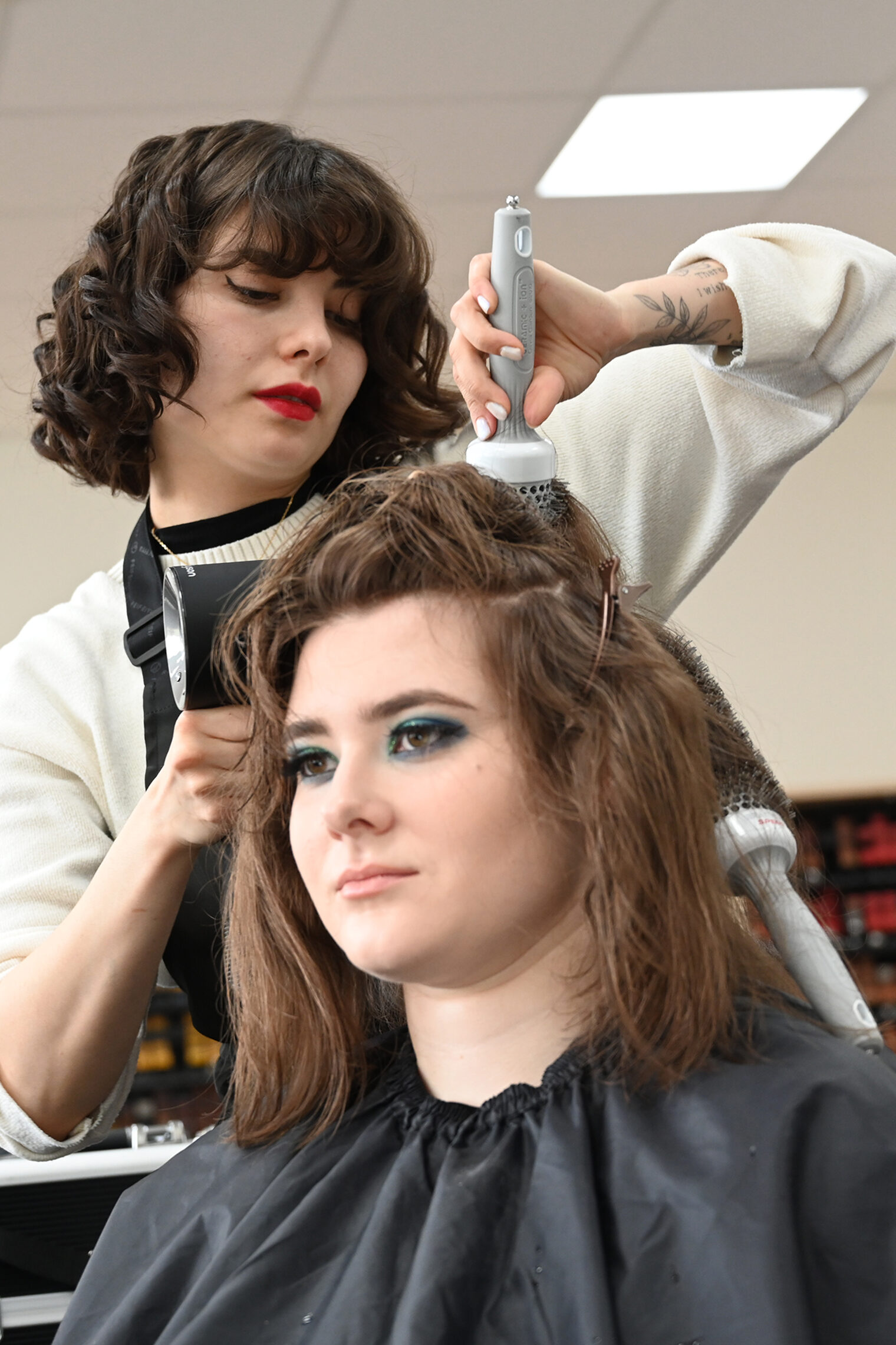 Friseurin föhnt Haare.