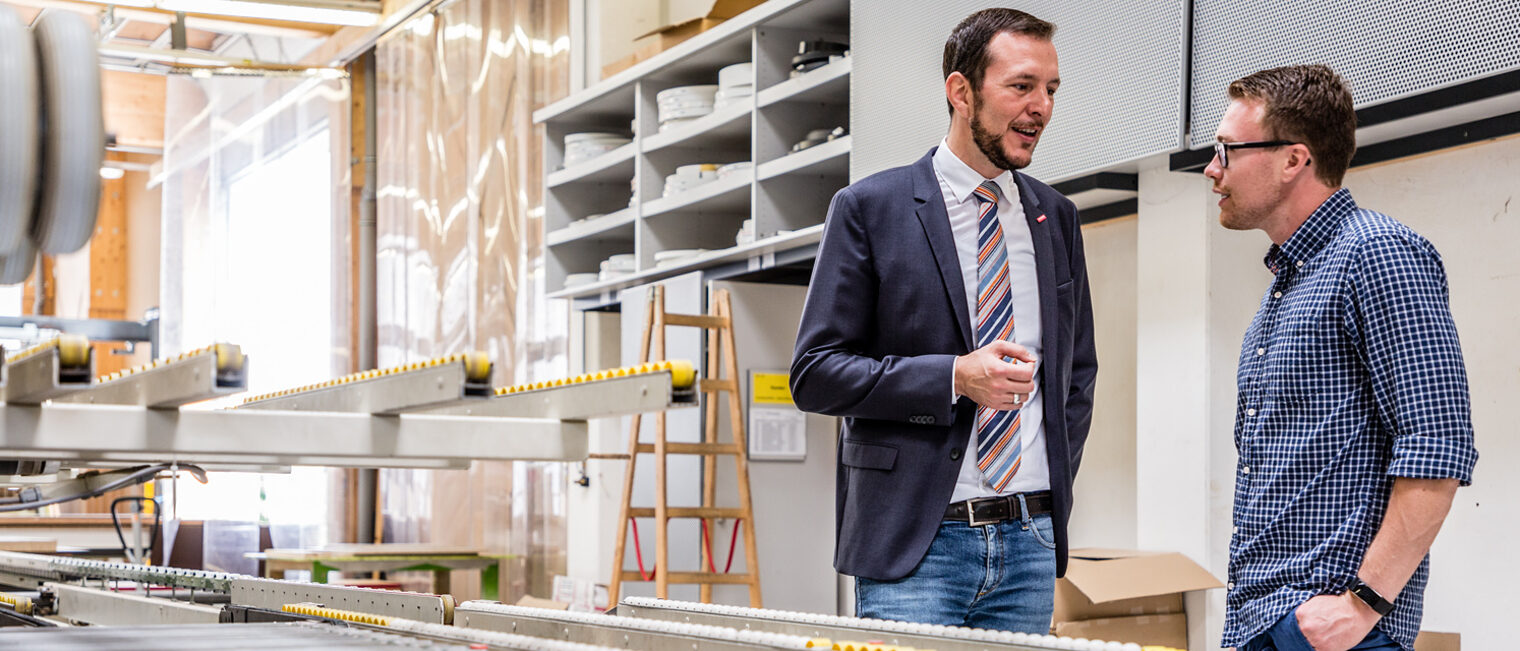 Beratung Berater und Betriebsinhaber im Gespräch an einer CNC-Maschine