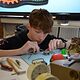 Schüler arbeitet an Uhrmechanik mit Pinzette an Tisch mit Werkzeugen