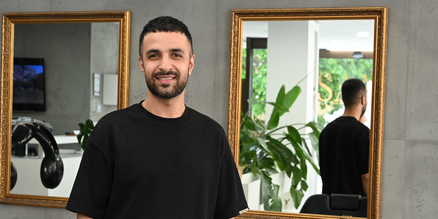 Friseurmeister in einem Salon schaut in Kamera