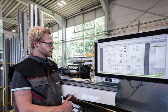 Ein Mann steht vor einem großen Bildschirm und prüft ein Gerät