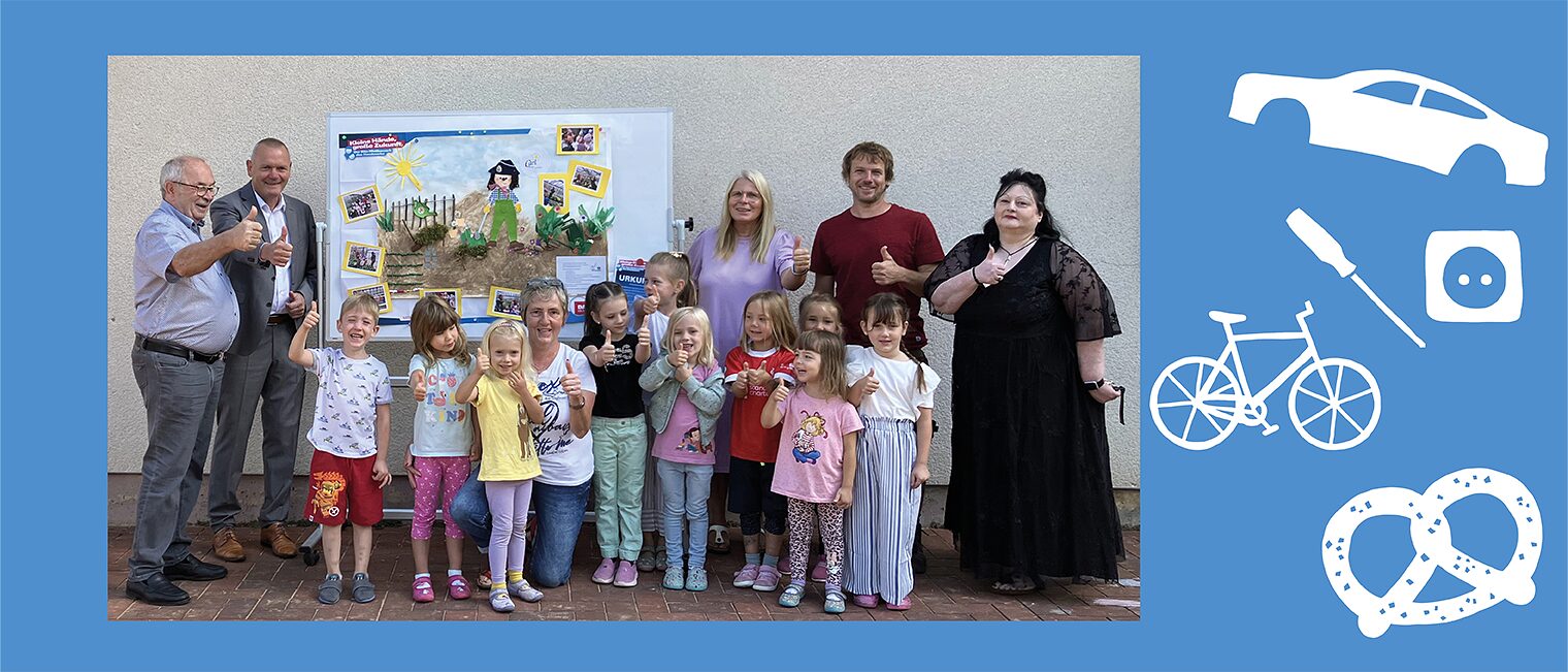 Kinder und Erwachsene vor einem von den Kindern gestaltenen Plakat.