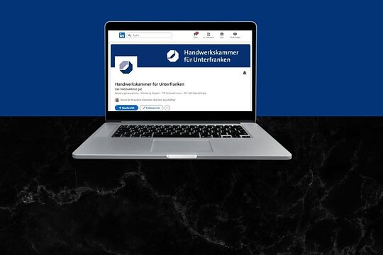 Man sieht einen Laptop. Auf dem Bildschirm sieht man die LinkedIn-Seite der Handwerkskammer für Unterfranken