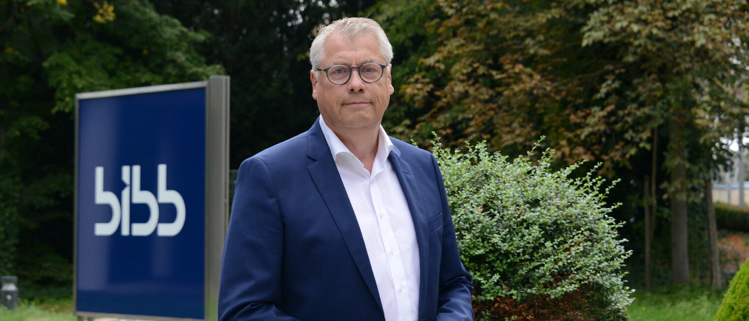 Porträtfoto draußen, im Hintergrund Stele mit Schriftzug "BIBB"