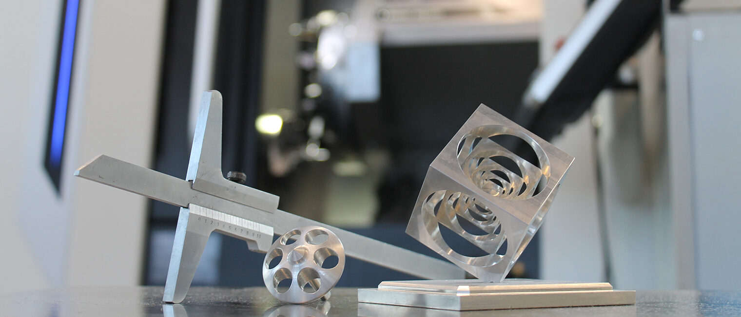 Präzisionsarbeit im Meisterkurs: Messschieber, gefräste und gedrehte Metallstücke vor moderner Drehmaschine