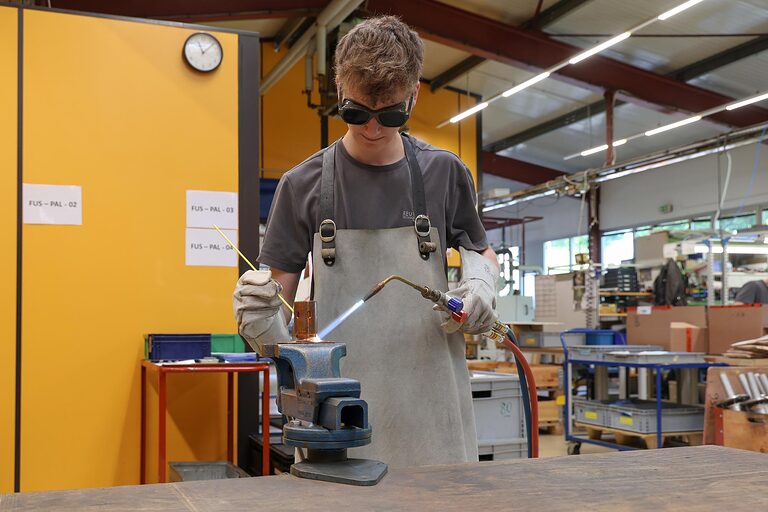 Junger Feinwerkmechaniker lötet