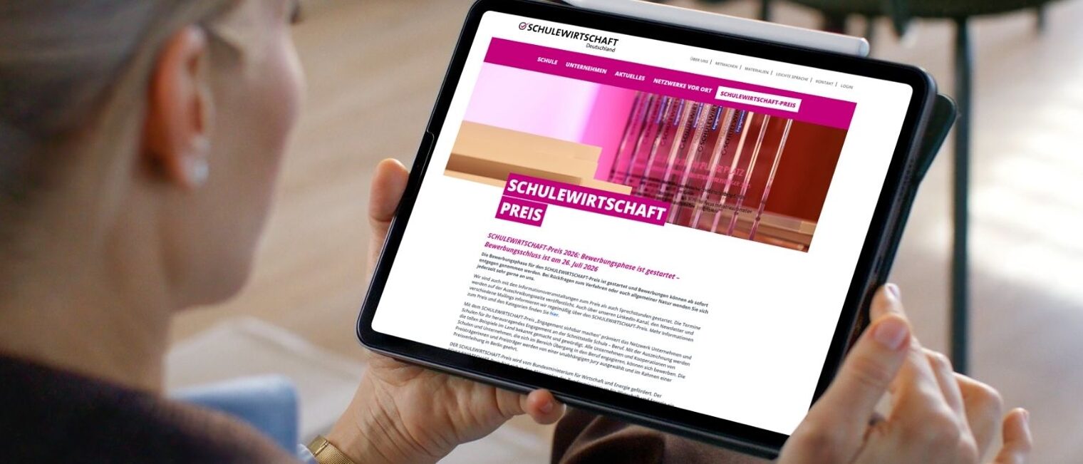 Frau schaut auf Tablet, auf dem die Startseite des Schulewirtschaft-Preises geöffnet ist