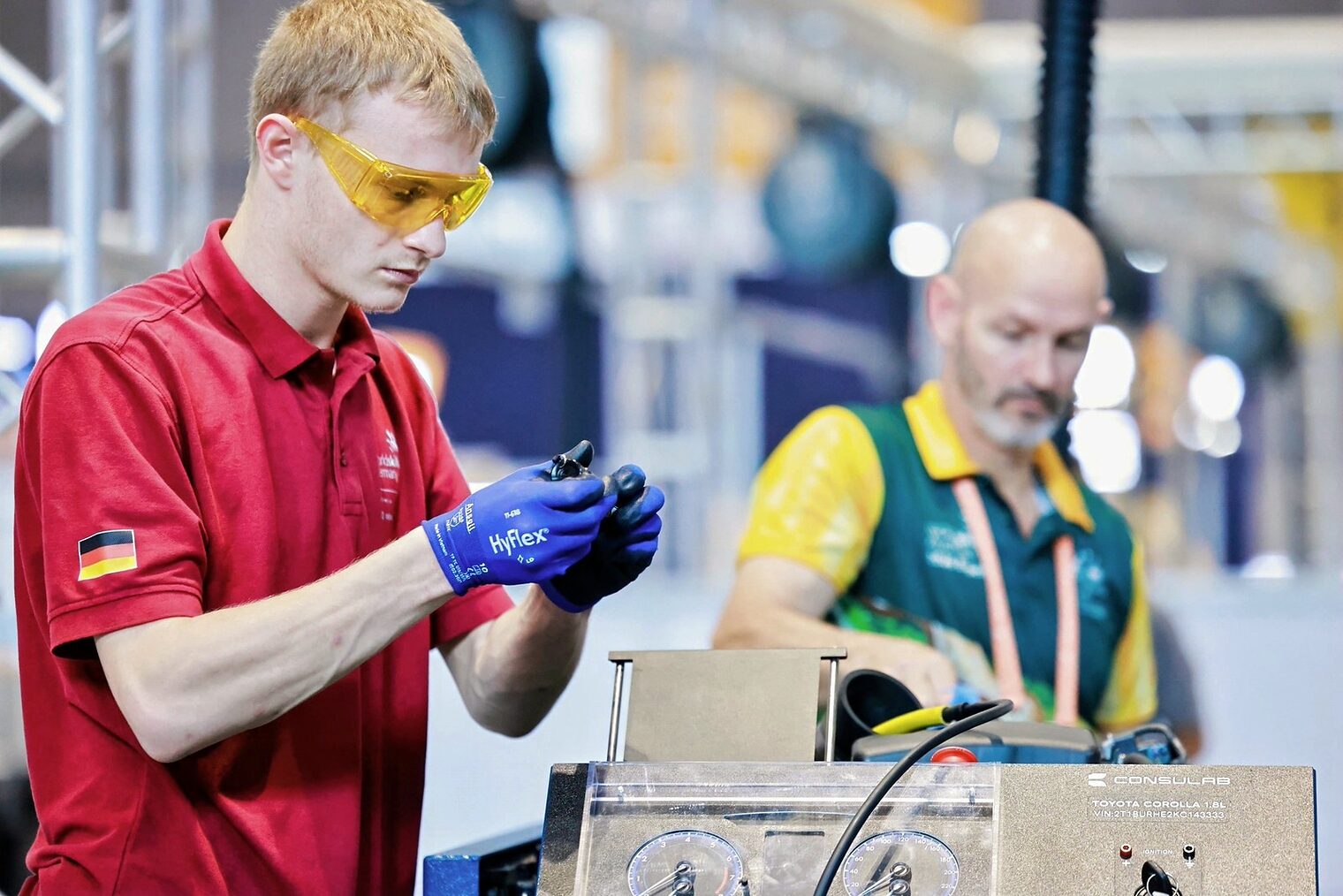 Junger Mann arbeitet mit Arbeitshandschuhen, Sicherheitsbrille an Autoaufbau