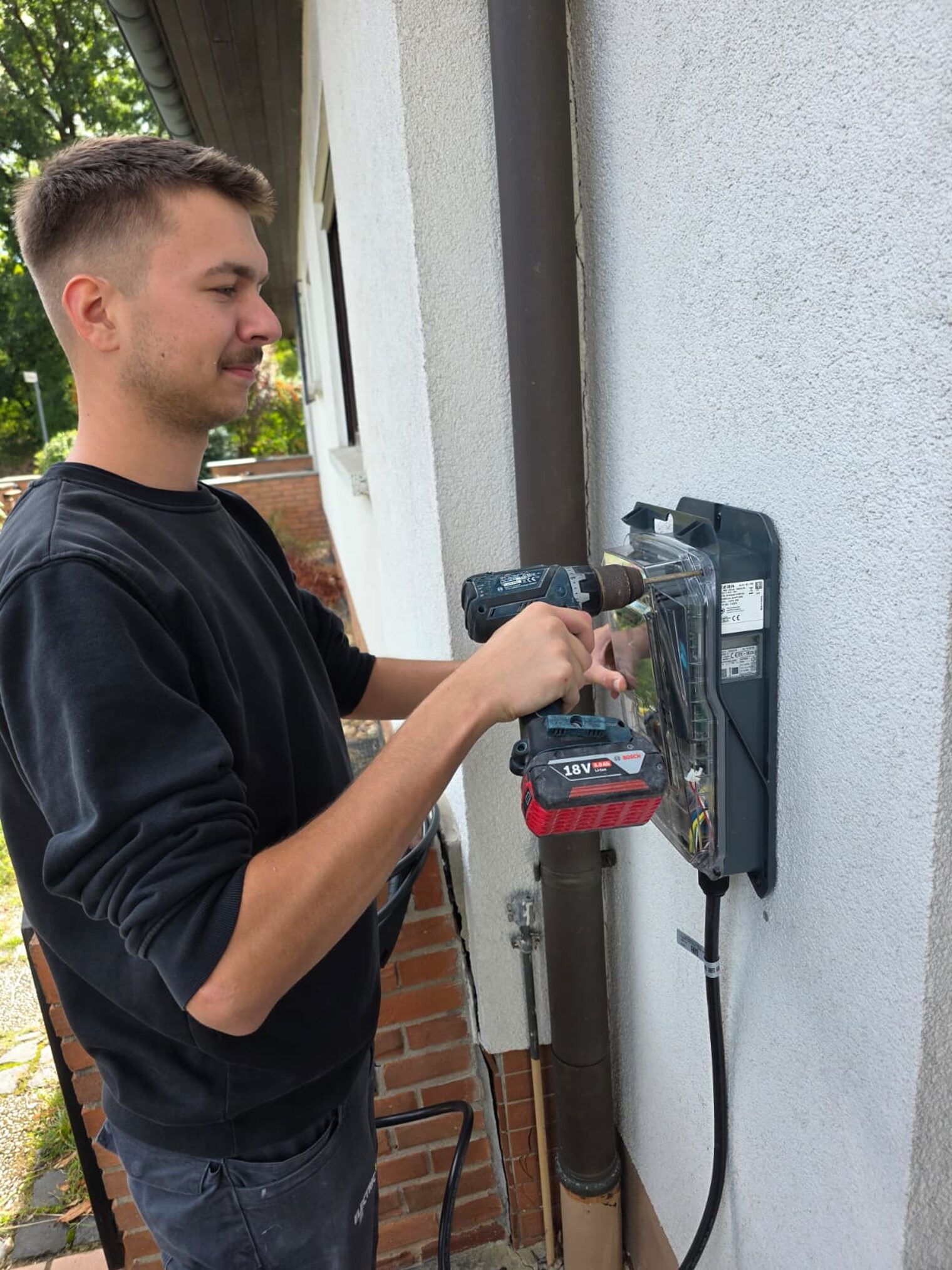 Elektroniker mit Akkuschrauber an einer Hausbox