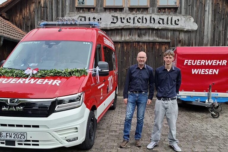 Zwei Personen bei Übergabe von Feuerwehrautos